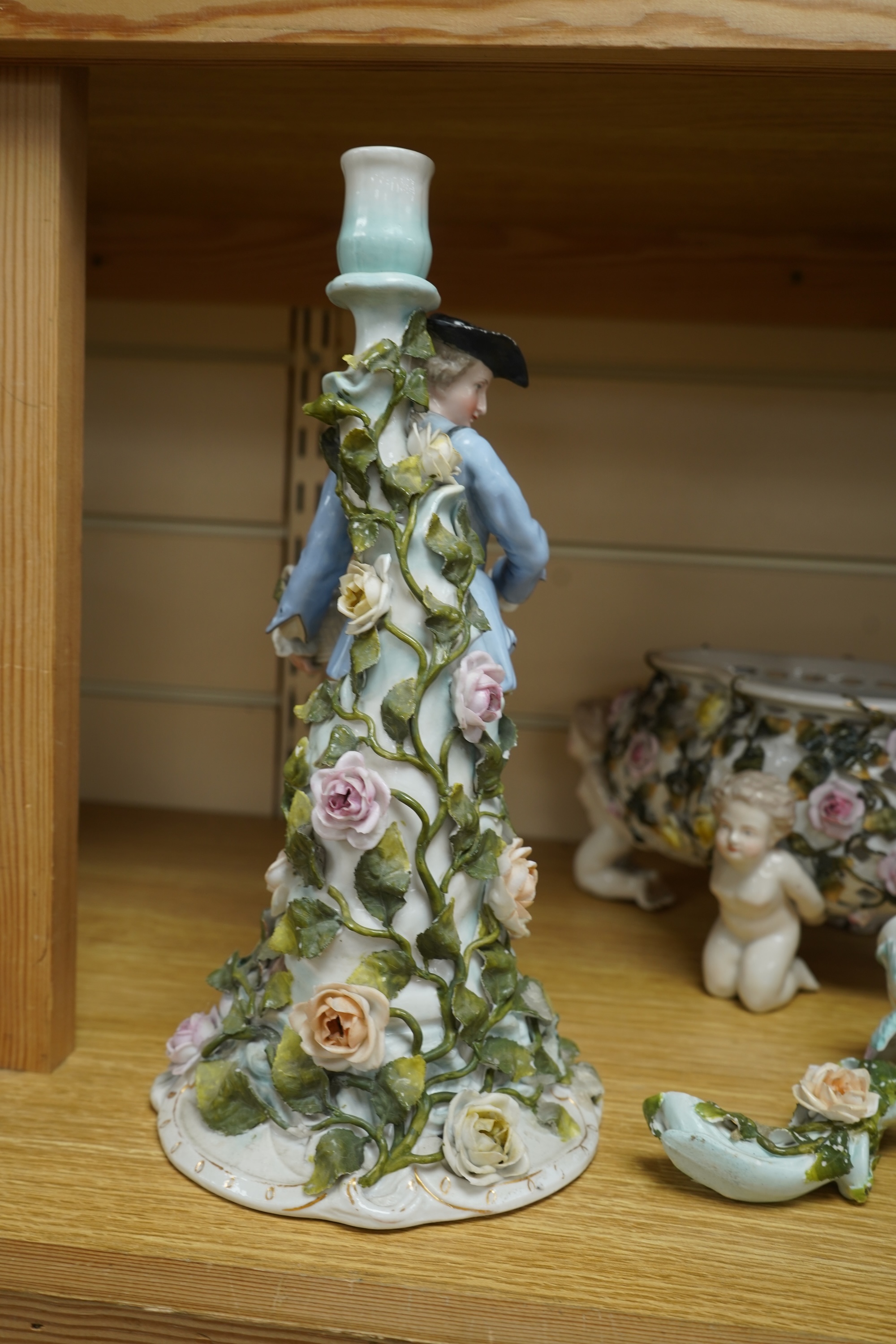 A German flower encrusted porcelain figural candelabrum, 30cm high, a cherub jardiniere and a cherub vase, all encrusted